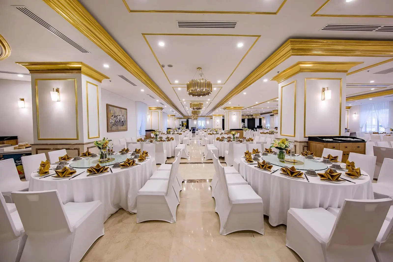 Sảnh tiệc trần vàng với bàn tròn phủ khăn trắng