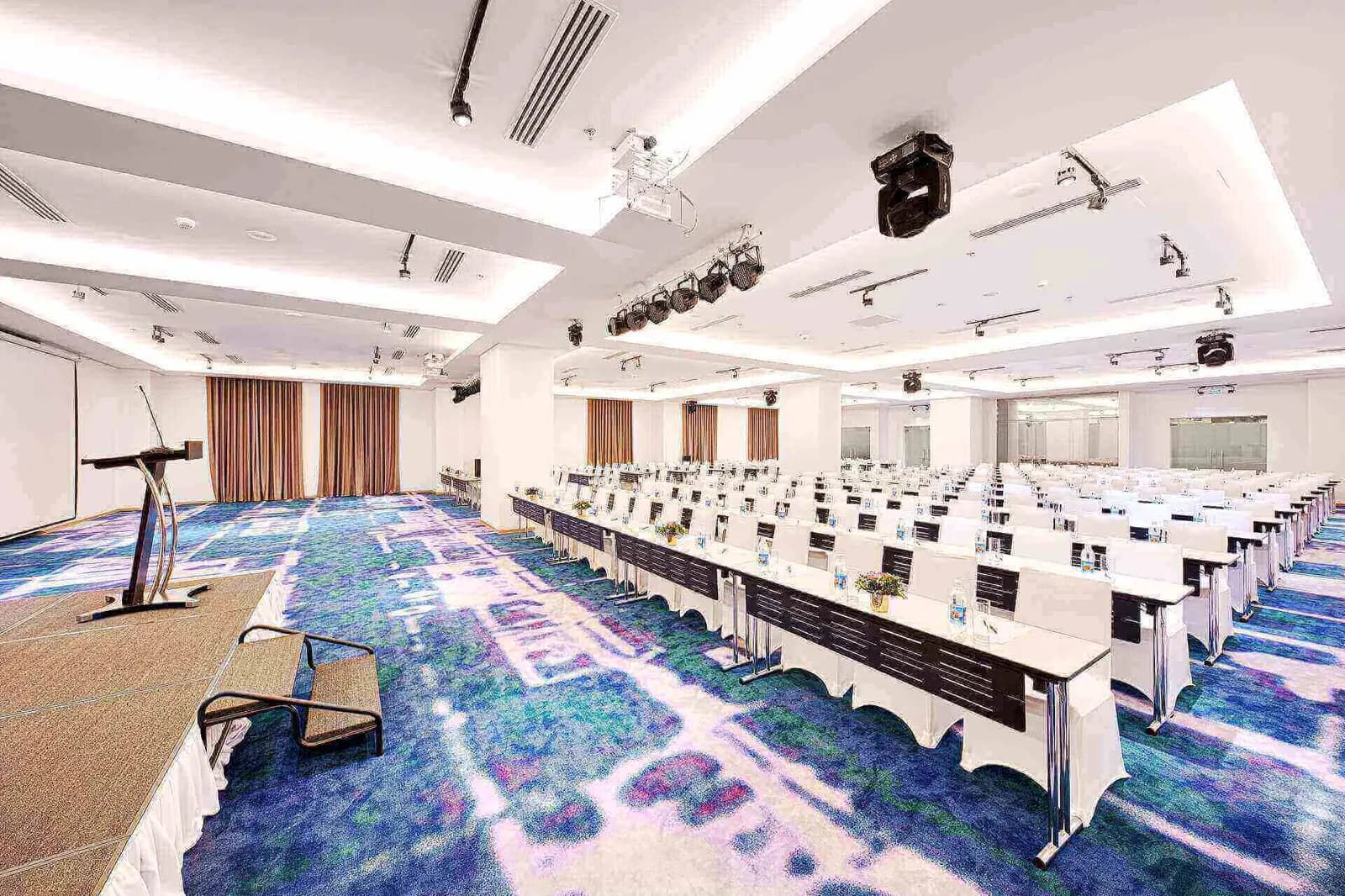 Phòng hội nghị bày bàn kiểu lớp học, ghế bọc trắng